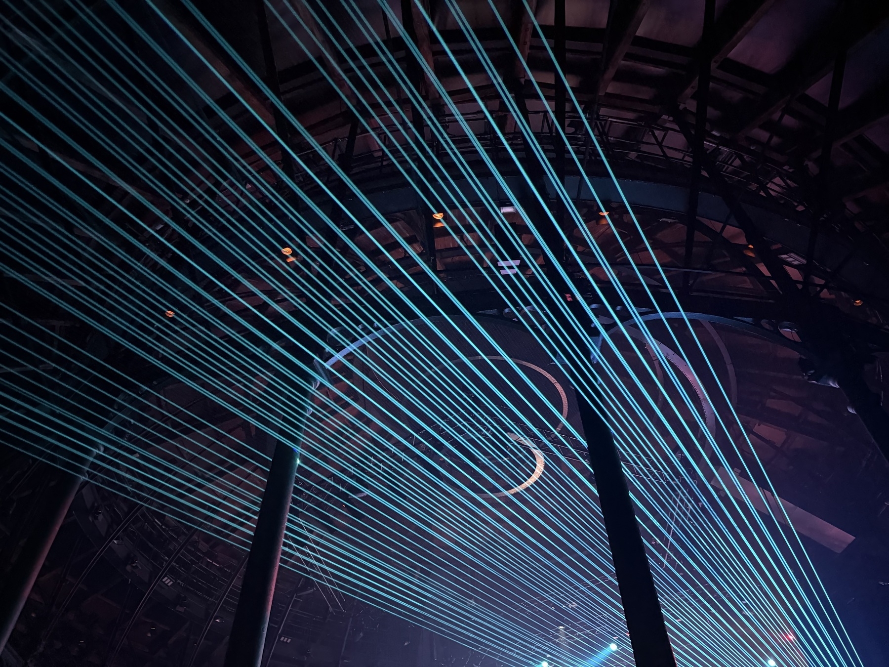 Lasers shining through the air beneath a metal structure.