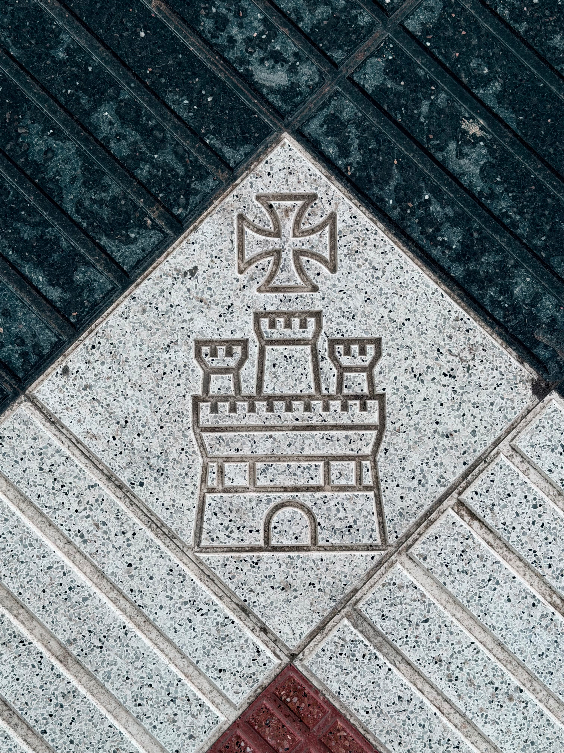 An engraved castle with cross above in a paving stone.