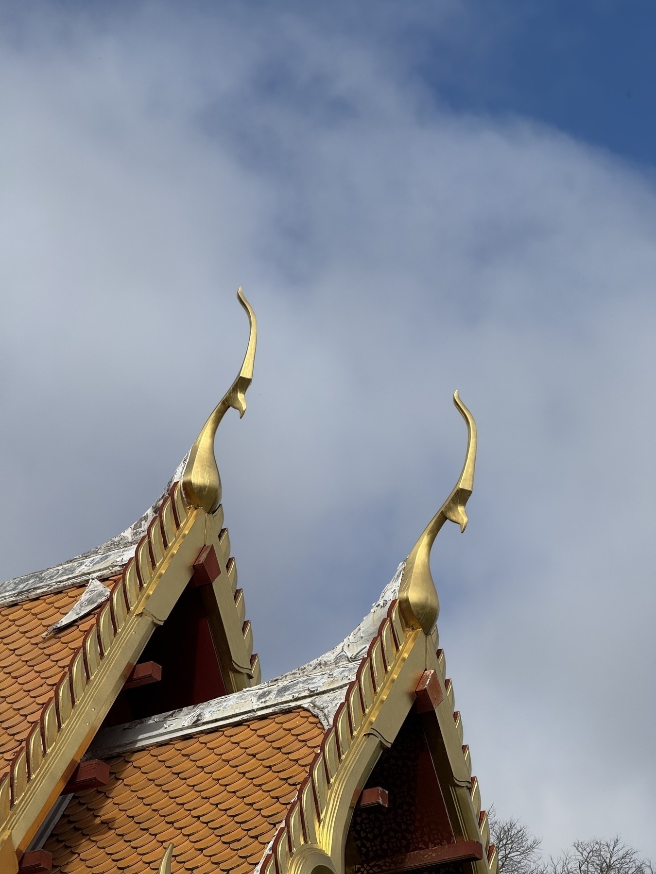 Gold sculptures on the ends of sharply pitched tiled roofs.