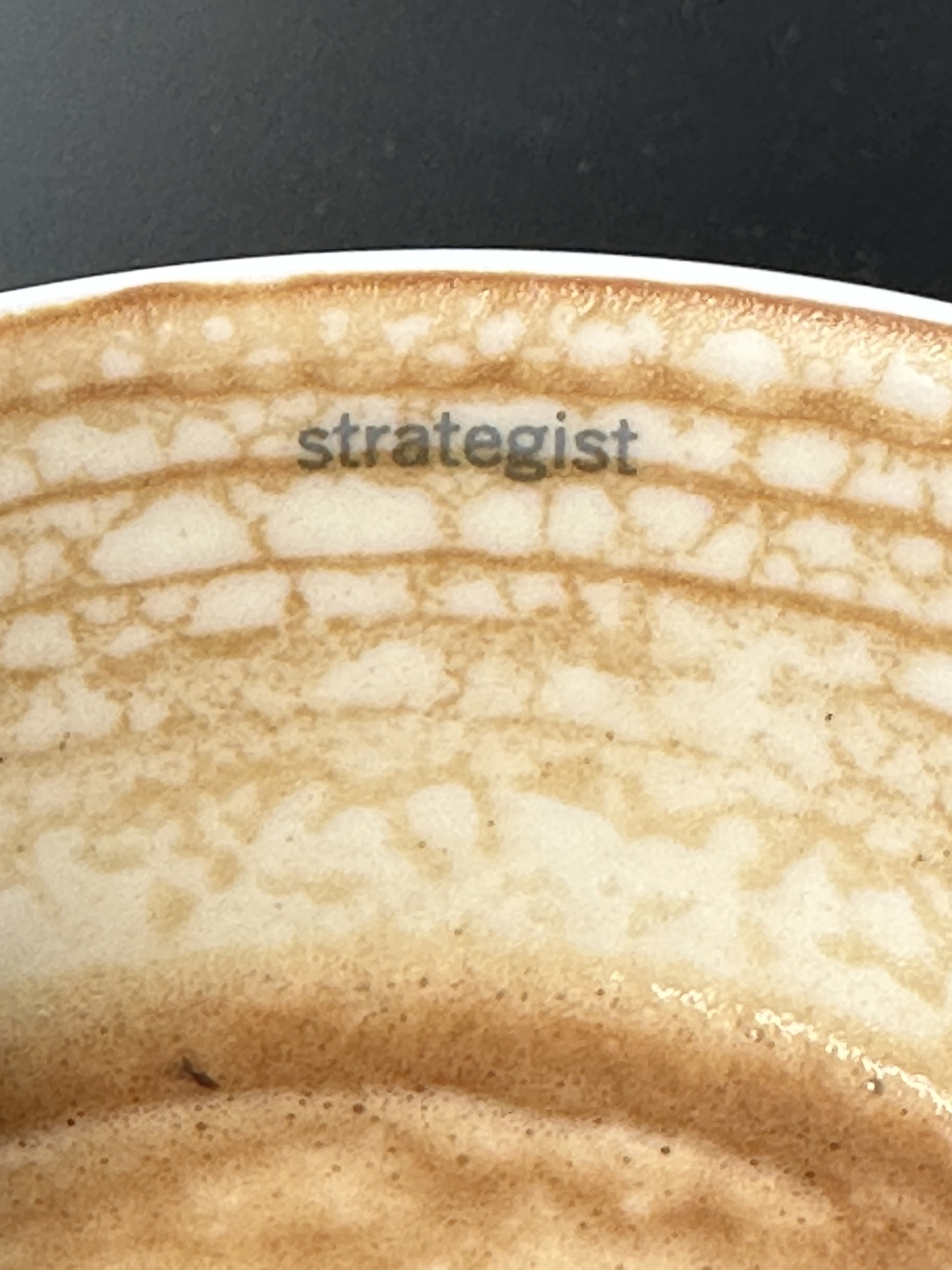 Picture of a latte with the word strategist marked on the inside of the cup.
