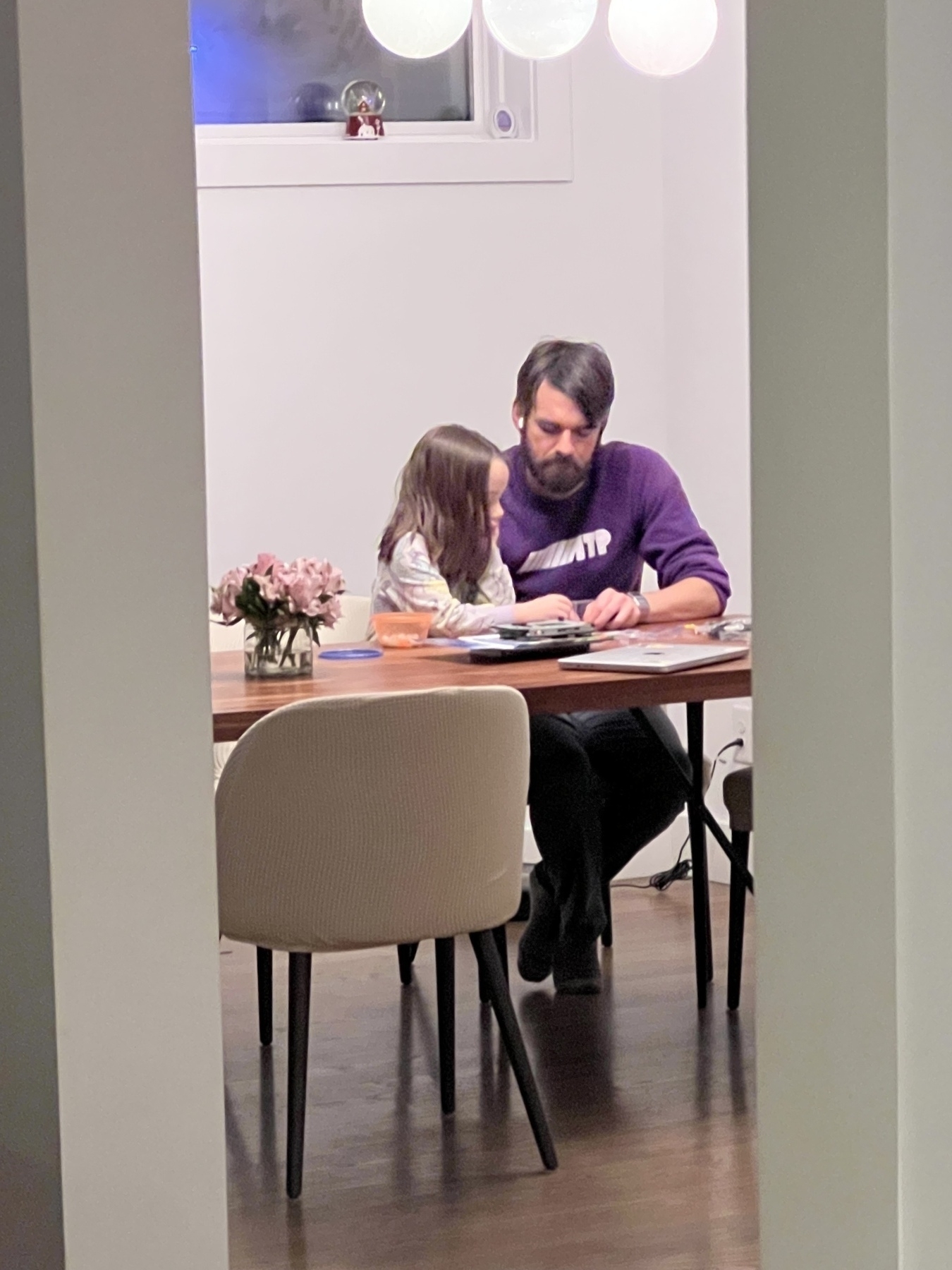 Me and my daughter sitting at a dining table with flowers, engaged in an activity together.