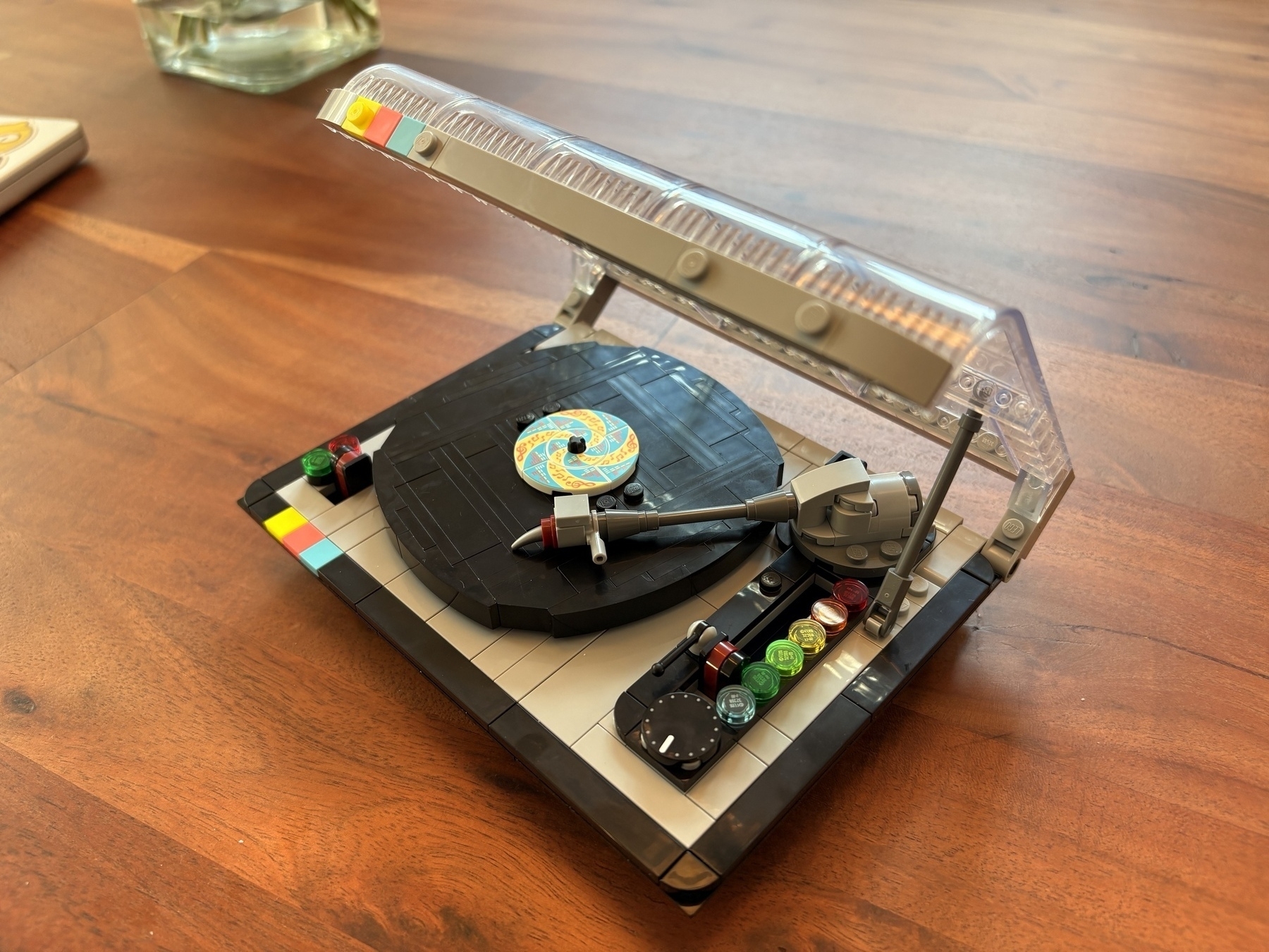 A LEGO model of a turntable sits on a wooden surface.