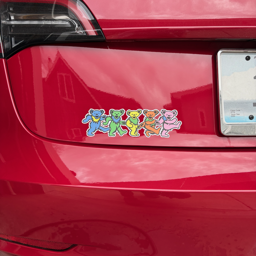 Auto-generated description: A red car features Grateful Dead dancing bear stickers near the rear license plate.