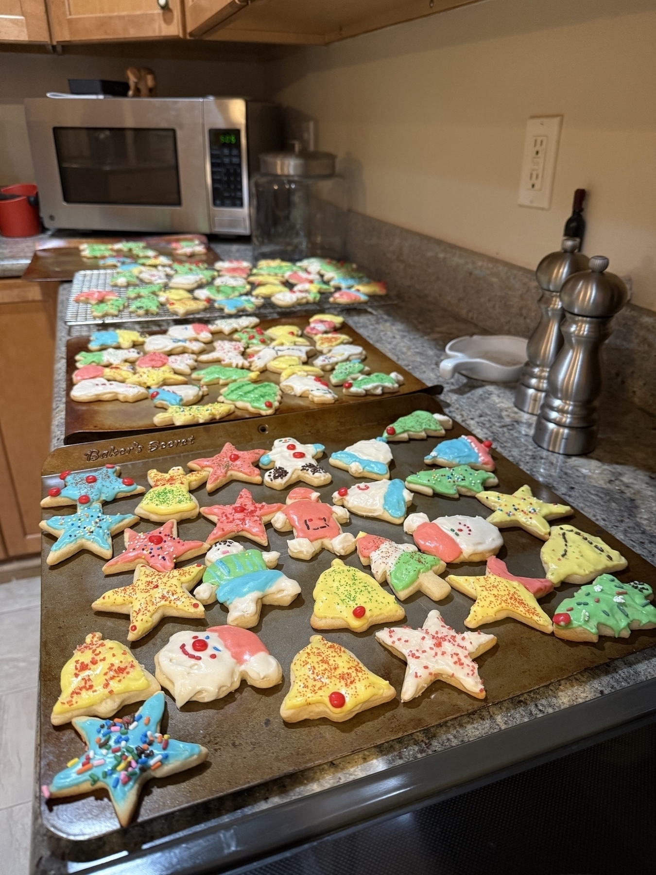 Several trays of brightly frosted, homemade sugar cookies. 