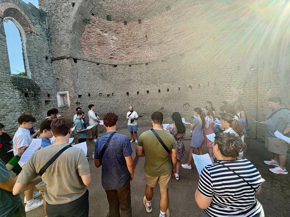 A group of people appears to be engaged in a guided tour or educational activity inside a historic, circular brick structure.