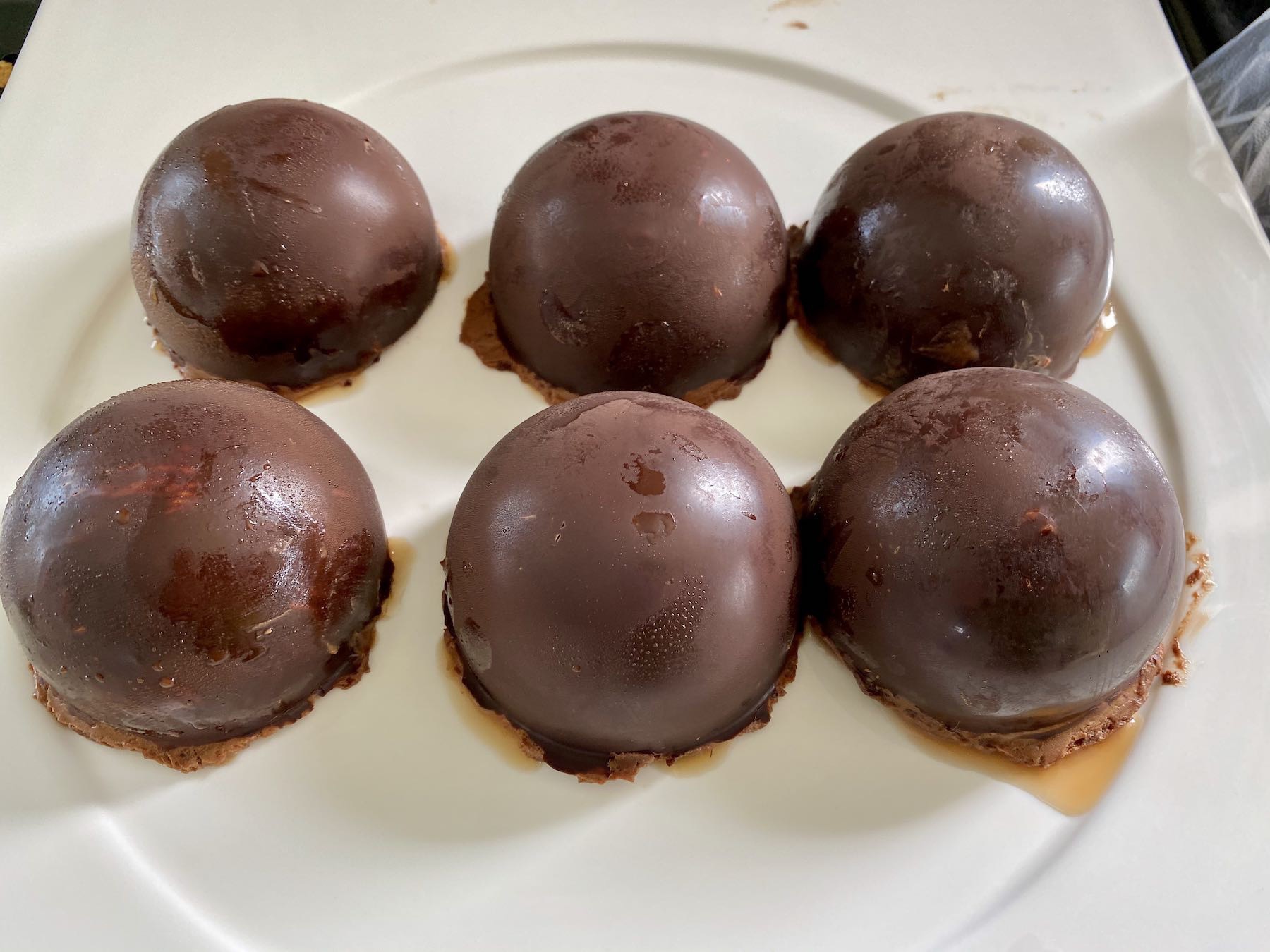 Chocolate mousse domes on a white plate. 