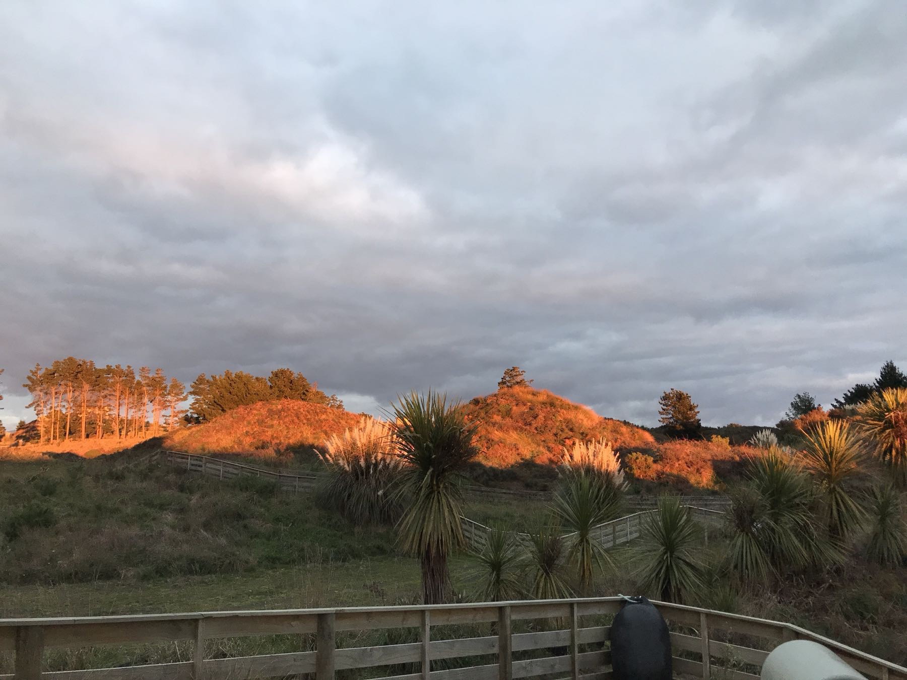 Golden light on nearby small hills and trees. 