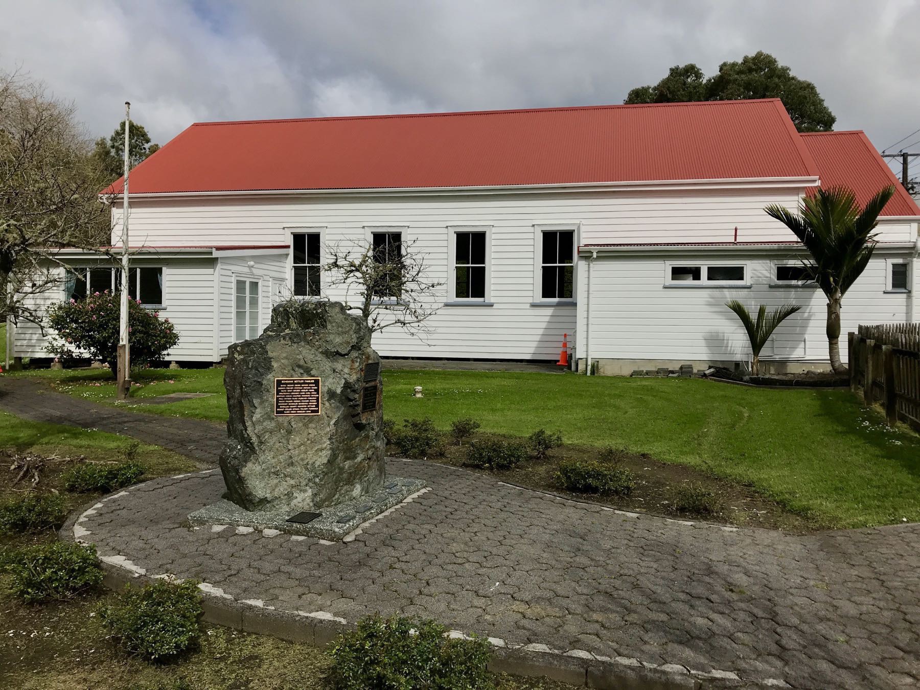 Building with memorial rock and plaque in front of it. 