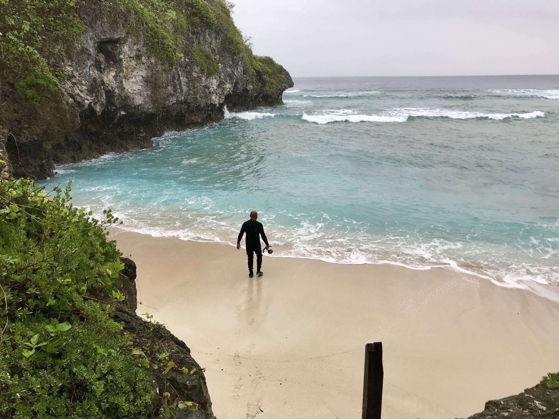 On the beach, a man gets ready to swim.