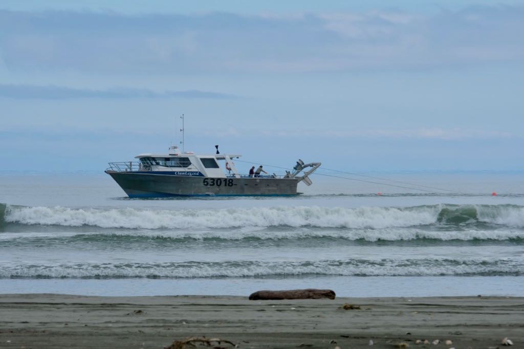 Fishing vessel 63018 Clam Legend near the shore. A couple of people can be seen working on deck.