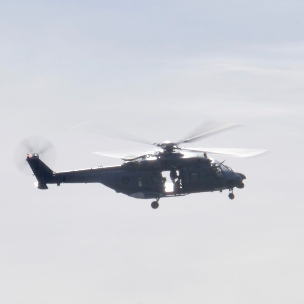 NH90 helicopter, showing open doors and people inside.