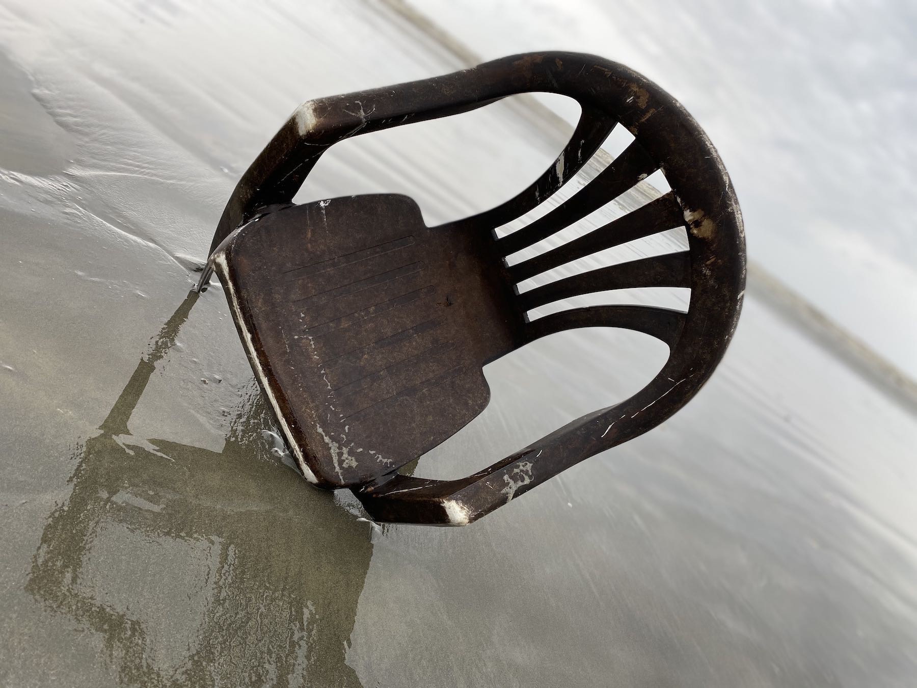 Plastic chair missing one leg., angled view.  