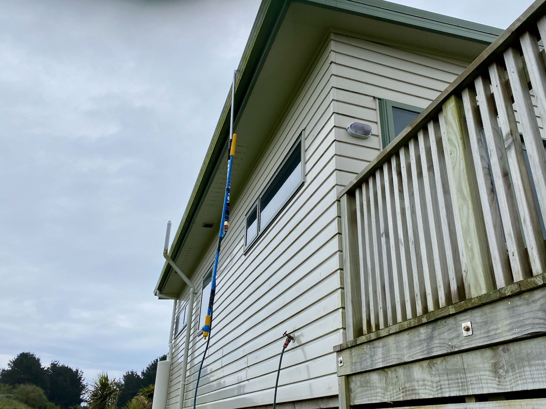 Closer view of hose and nozzle hanging from the gutter. 