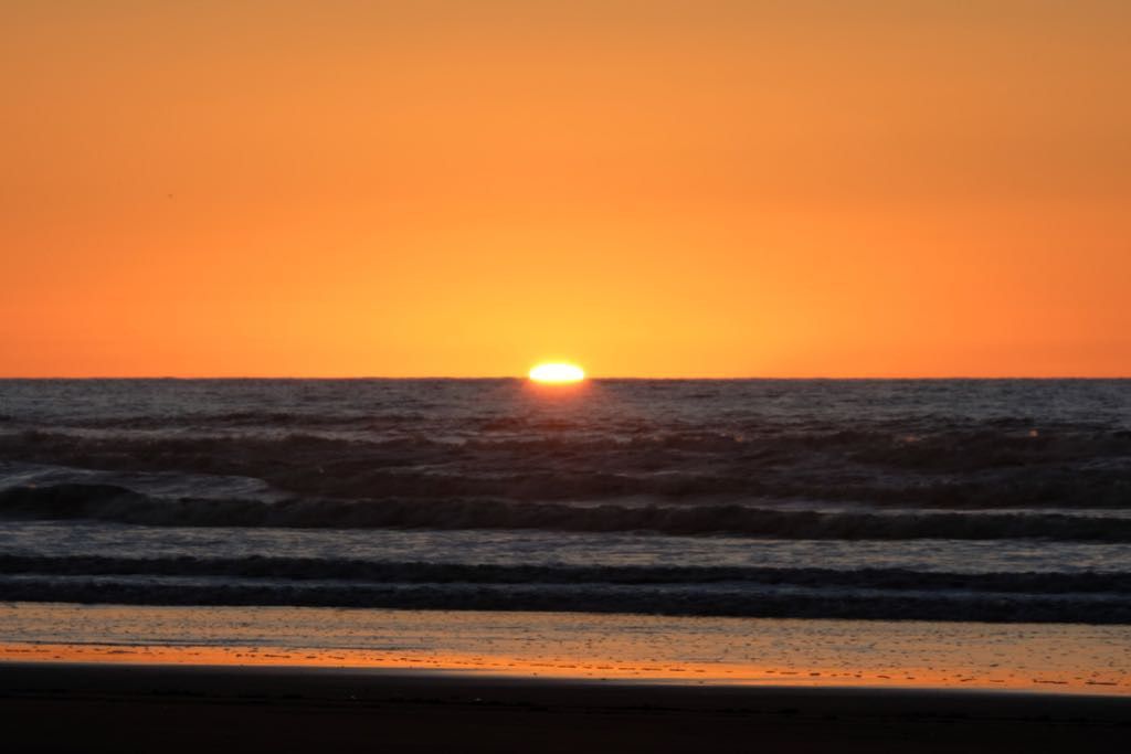 The sun almost below horizon across the sea. 