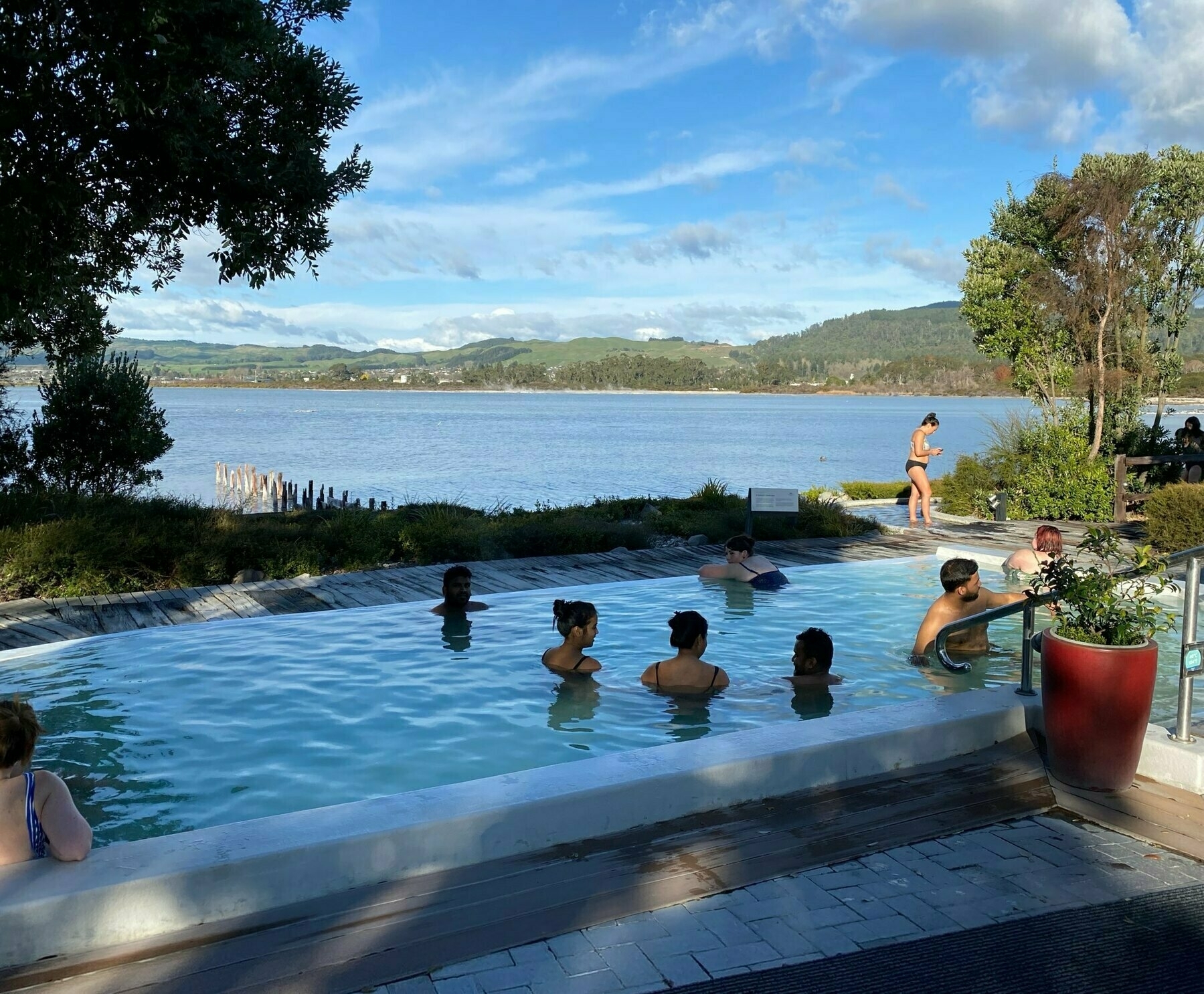 People in a thermal spa with Lake Rotorua behind. 