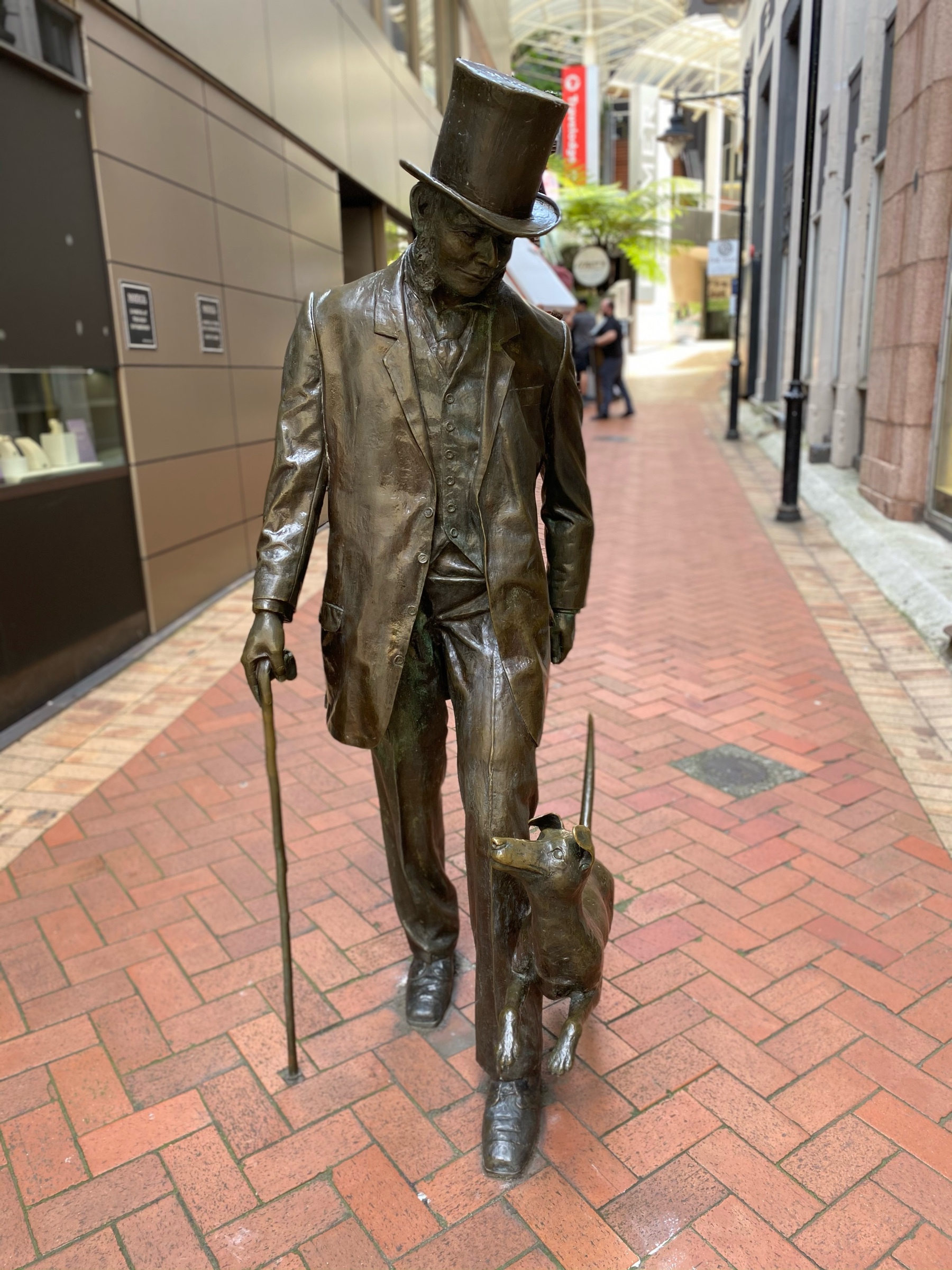 Statue of a man in a top hat with a small dog by his foot. 