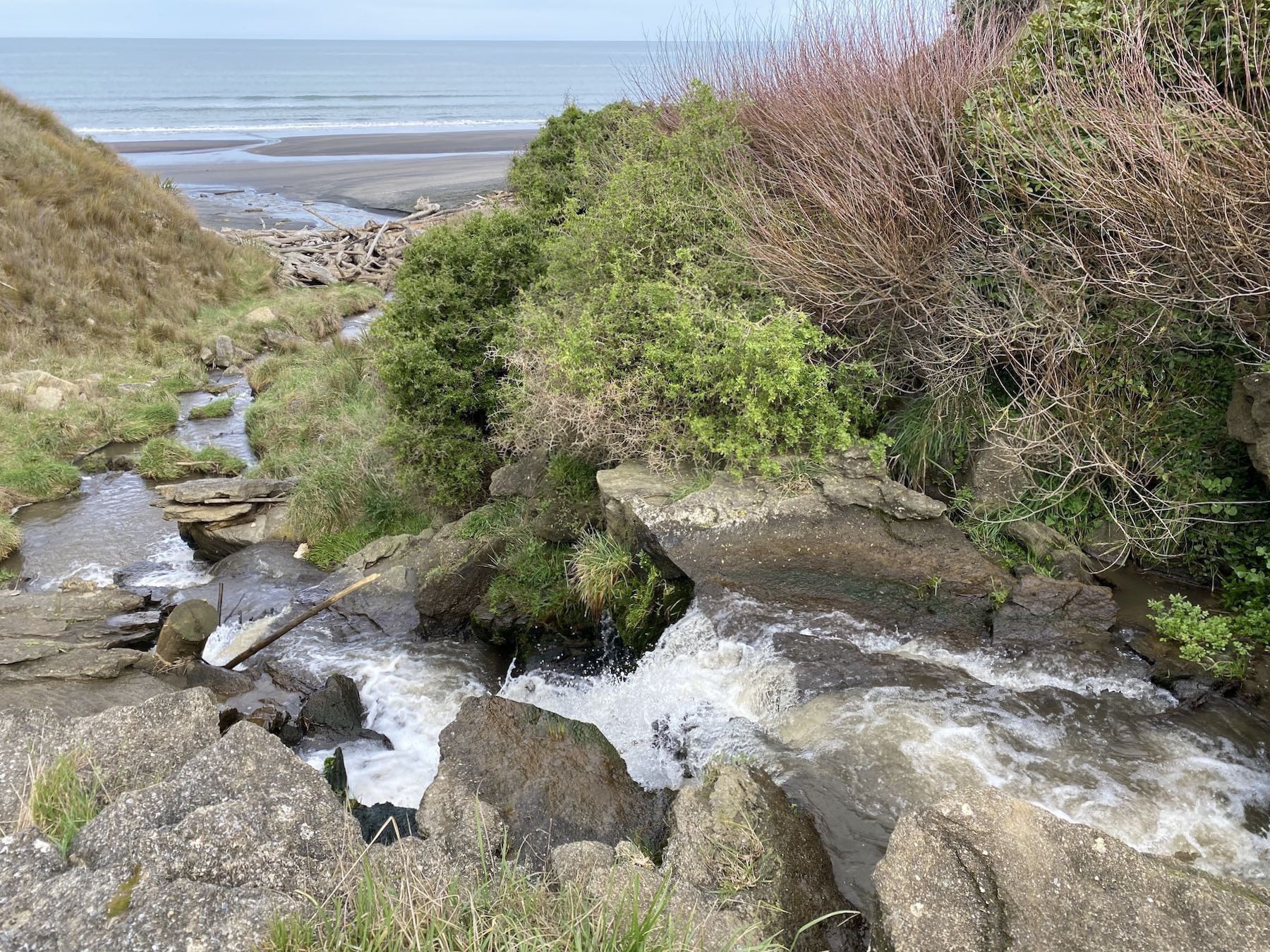 The lower waterfall, about 1 metre high, near beach level and flowing out to sea. 