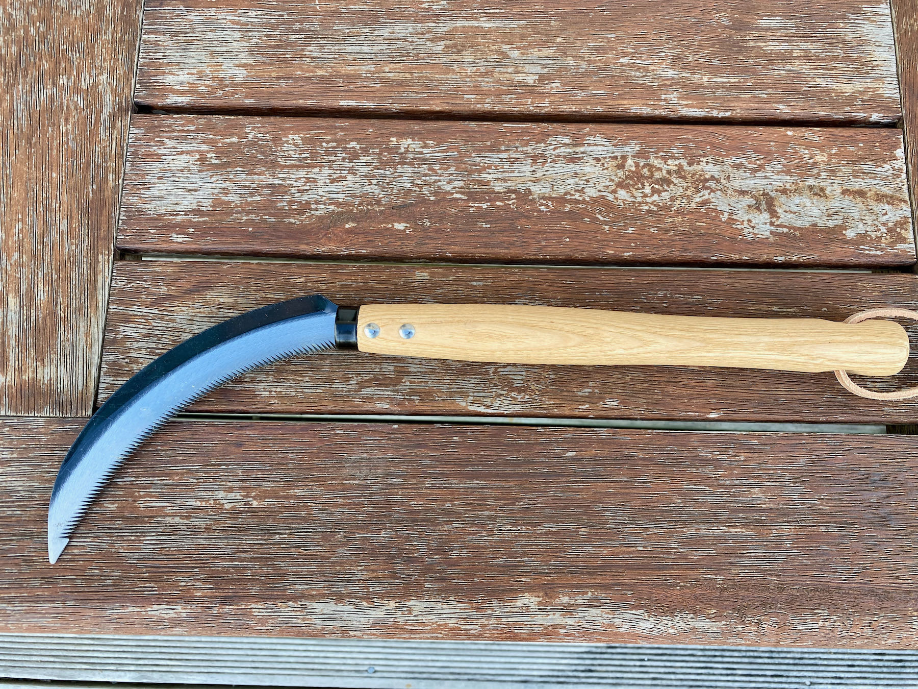 Long handled knife with a curved blade with numerous small sharp teeth. 