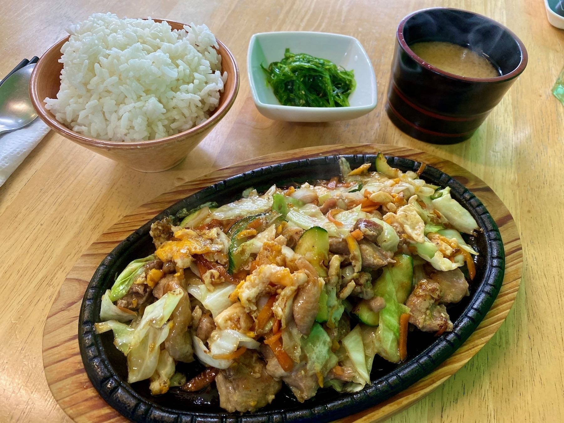 Plate of chicken teriyaki, bowls of rice, seaweed and miso. 