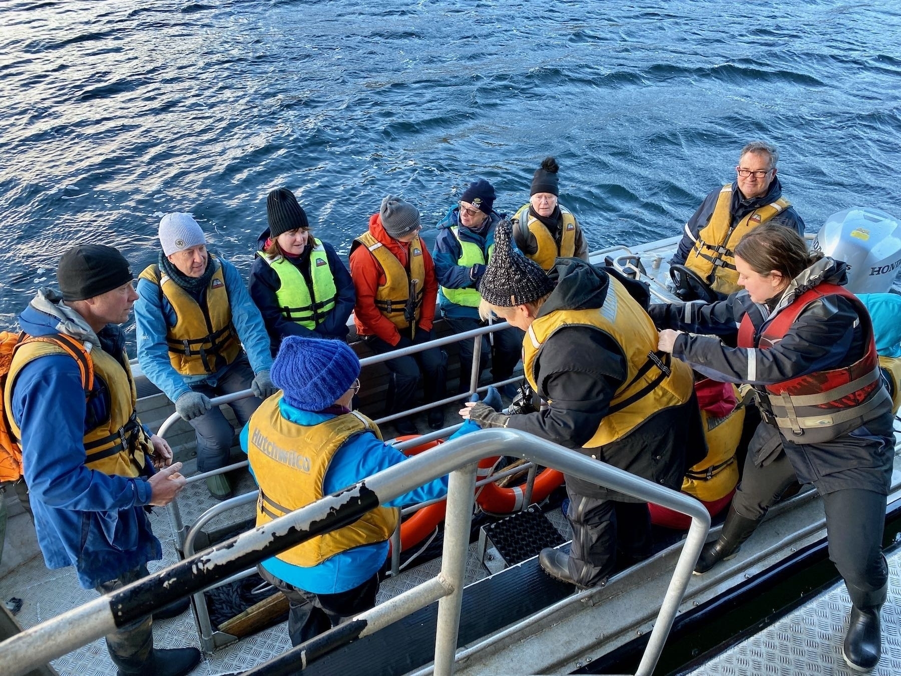 People in the tender, with one person ebing helped to board. 