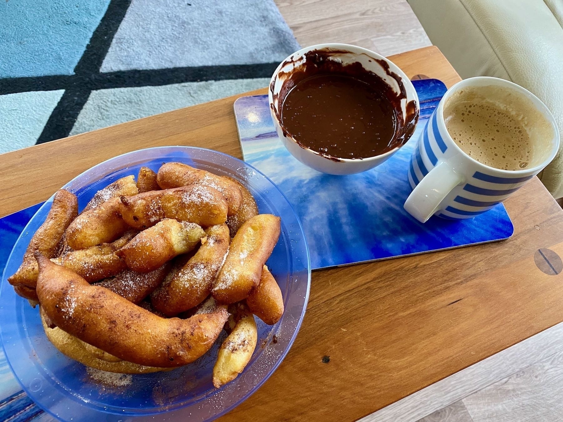 A plate of churros, chocolate dipping sauce and a cup of coffee. 