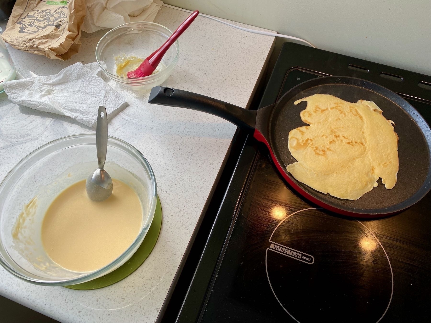 Bowl of mixture and crepe pan with batter cooking. 