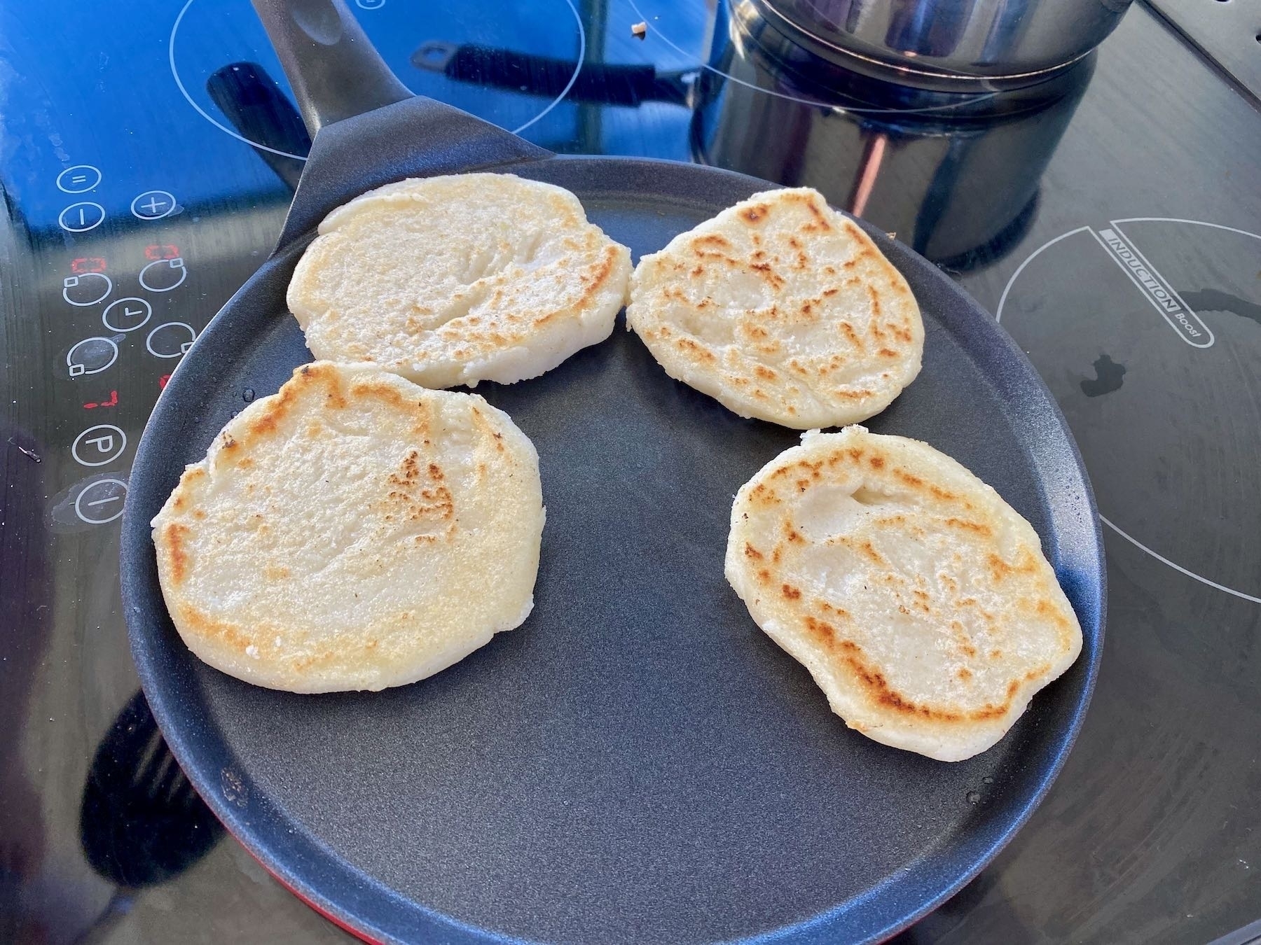 Arepas cooking on a crepe pan. 