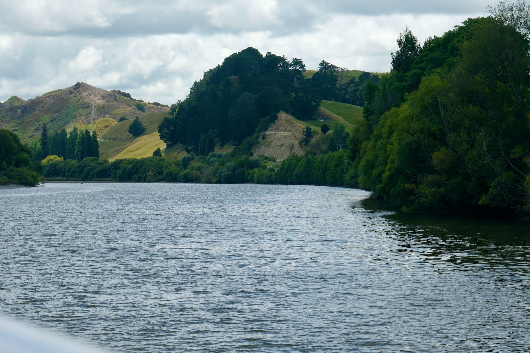 Broad river with green hills and verdant greenery. 