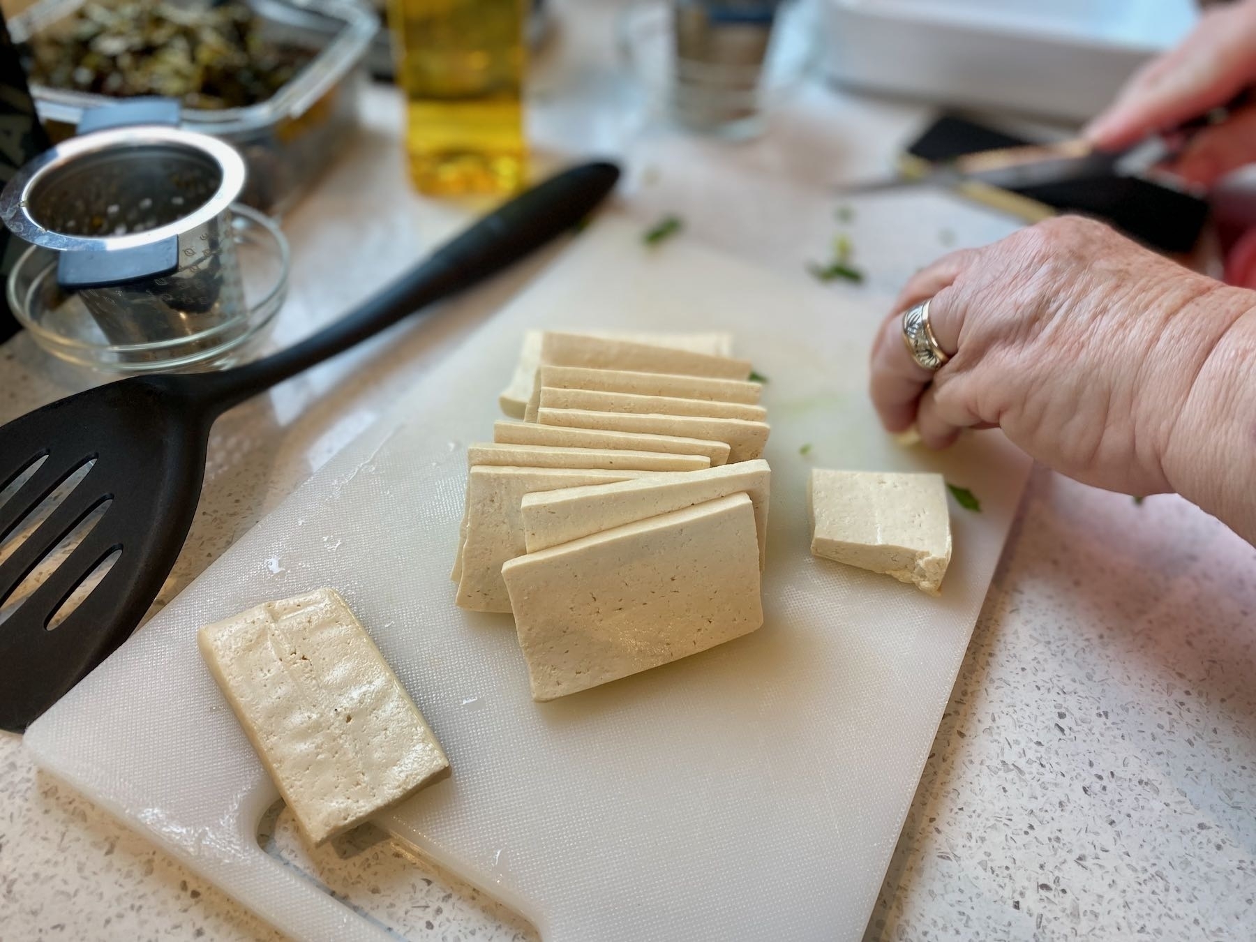 Tofu being sliced on a board. 