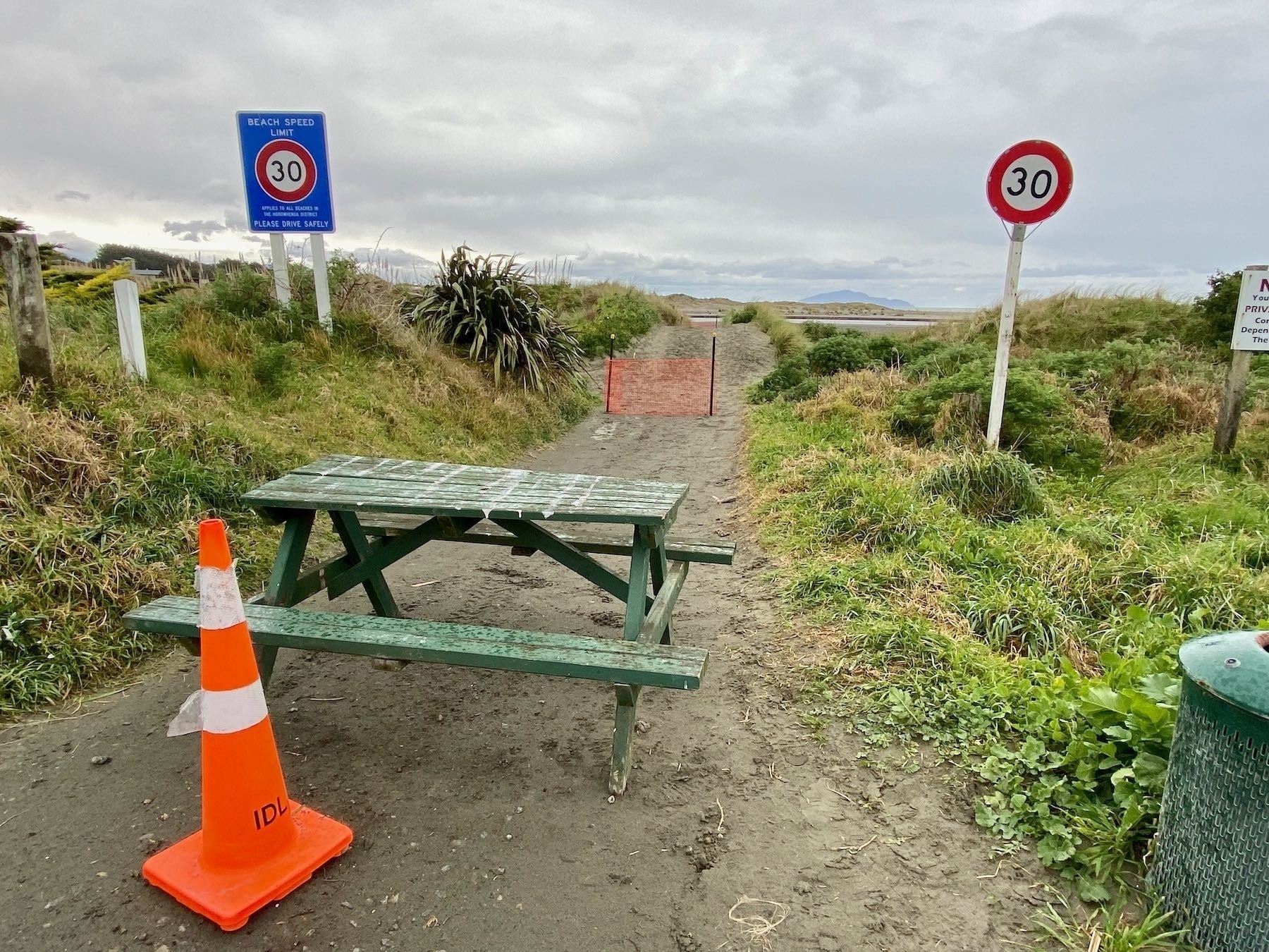 Picnic table, cone and temporary fence across the beach access road. 