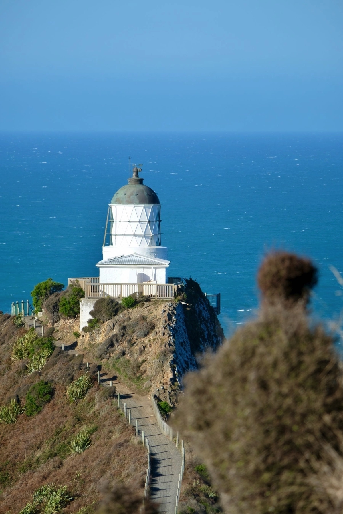 Nugget Point, Tokata, white lighthouse against deep blue sea. 