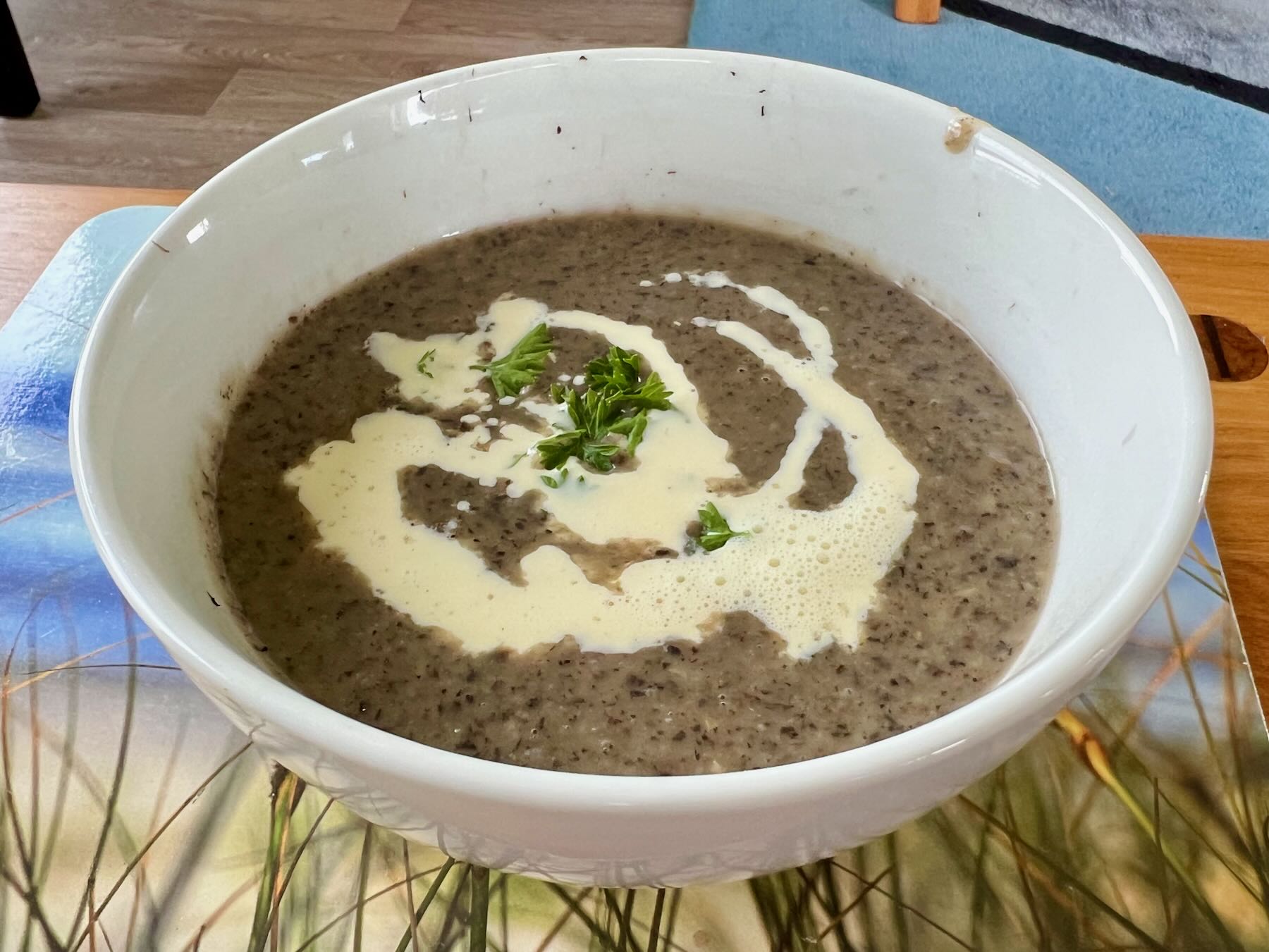 A bowl of mushroom soup with a little parsley and a swirl of cream. 