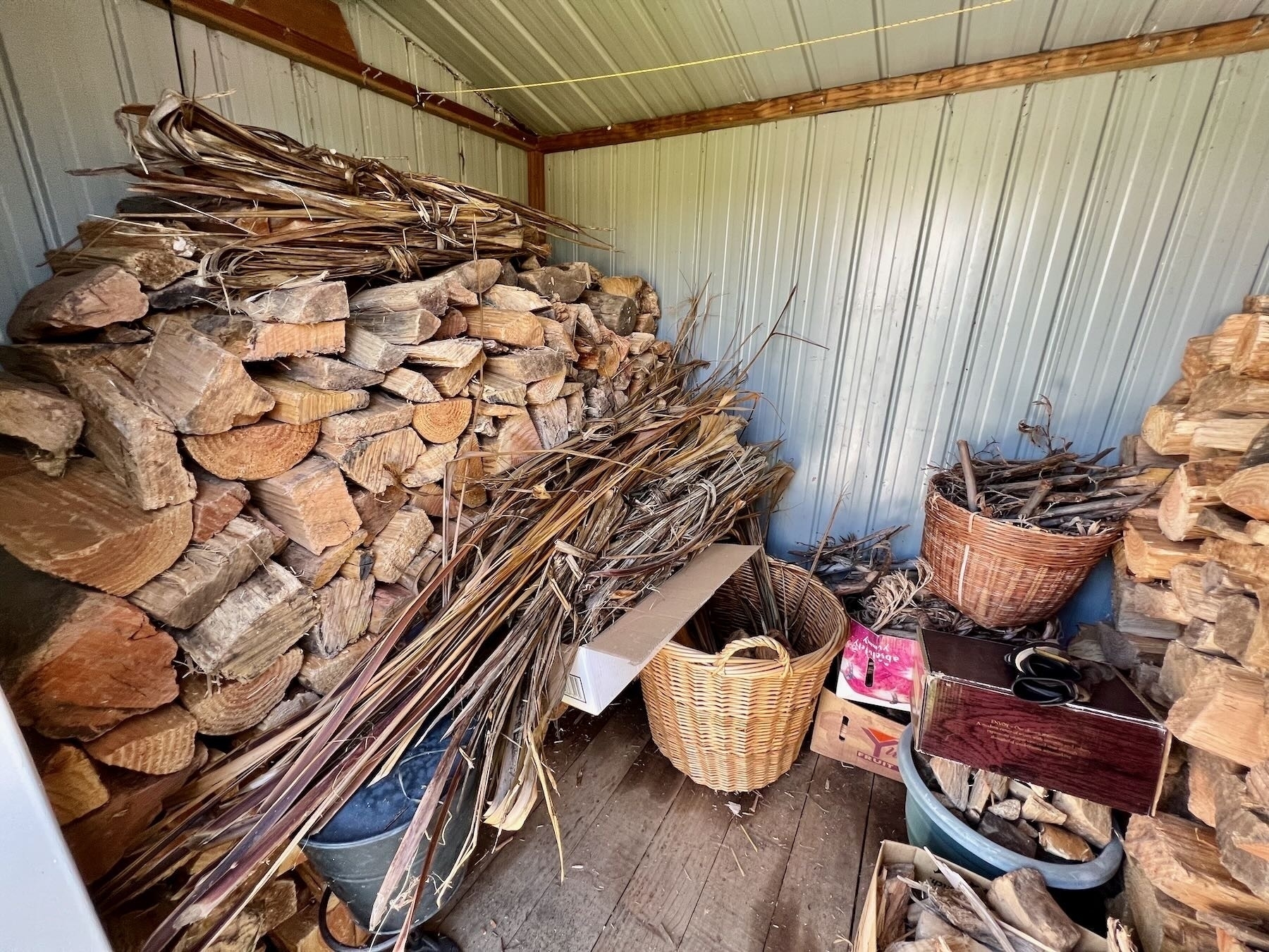 Stacked firewood on left side of the shed. 