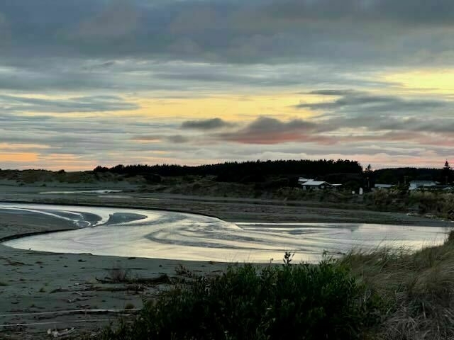 A loop of river exiting onto the beach with a dawn sky. 