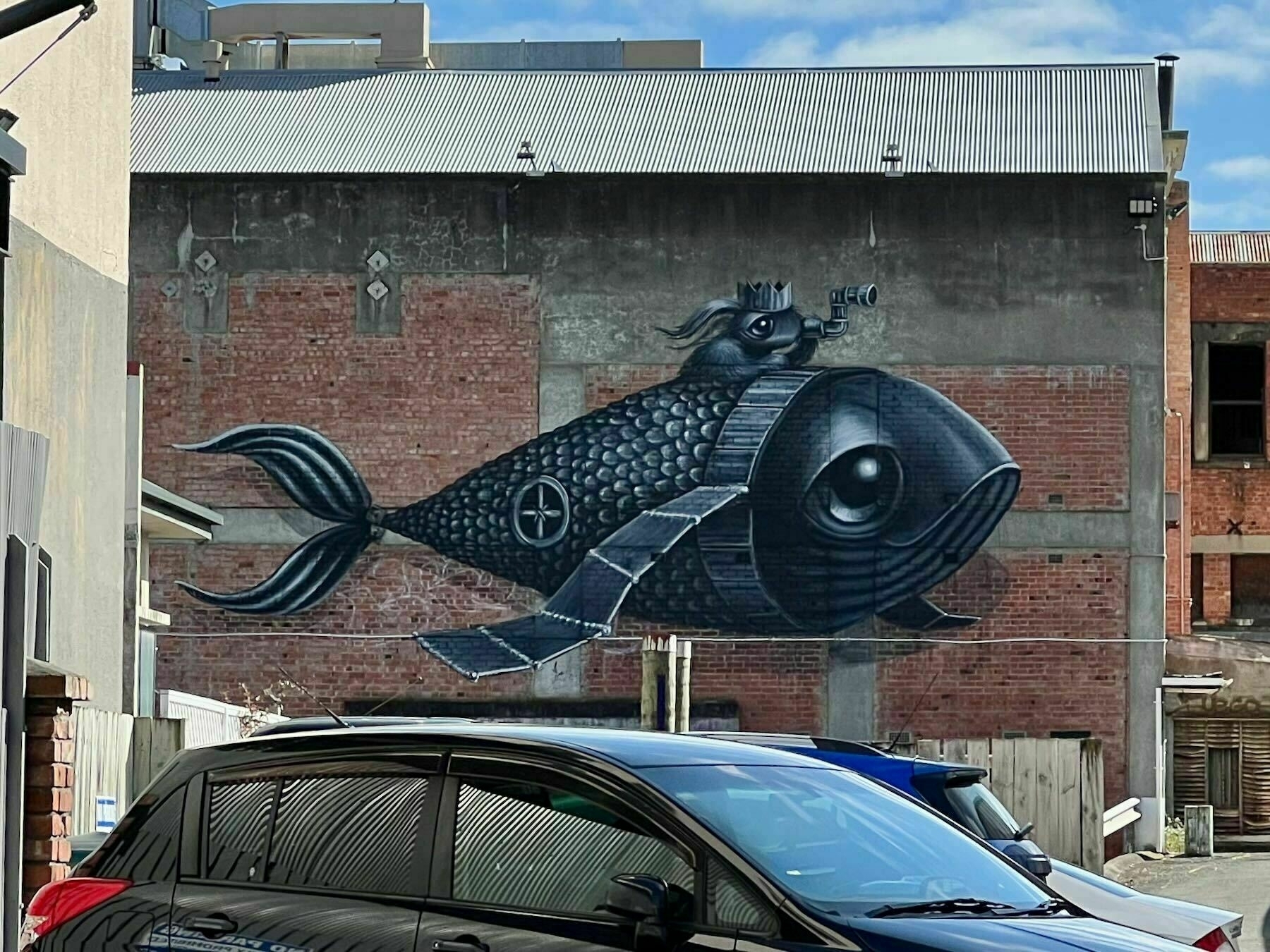 Mural depicting a black mechanical fish with a smaller fish on its back and using a periscope. 