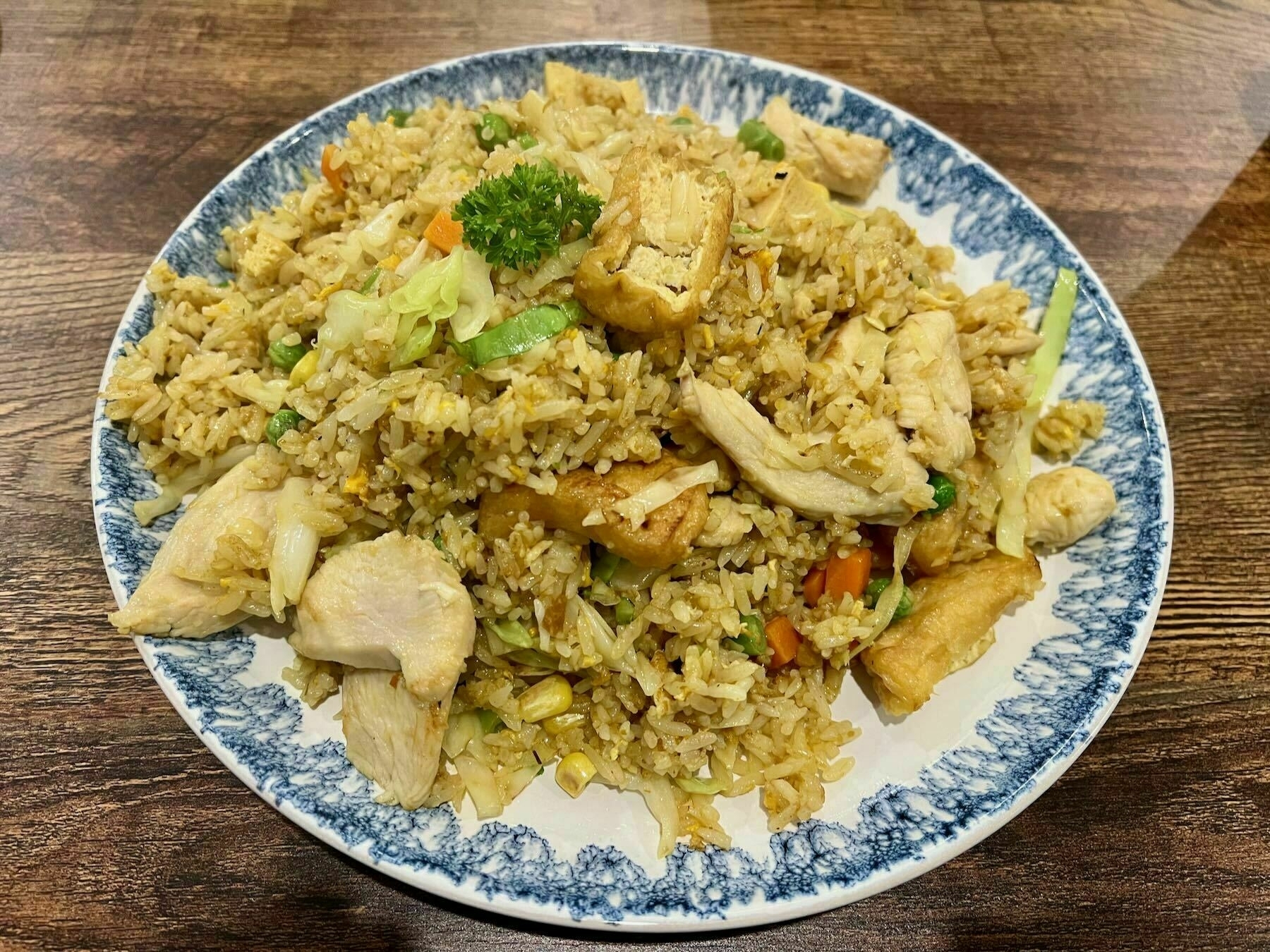 A large plate of rice with vegetables, chicken and tofu.  