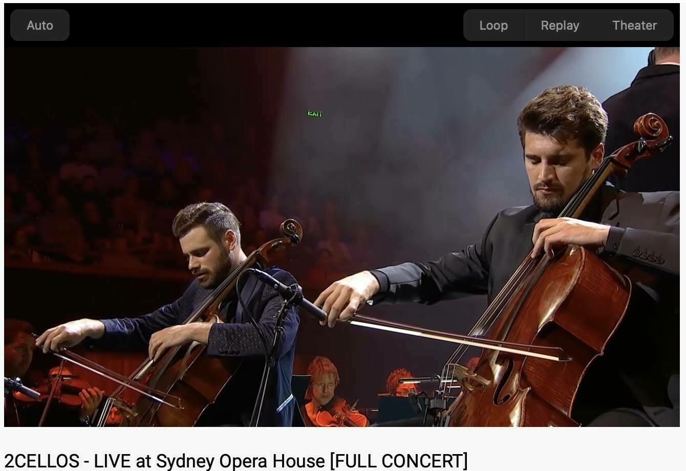 Screen Shot showing two  cellists with an orchestra. 