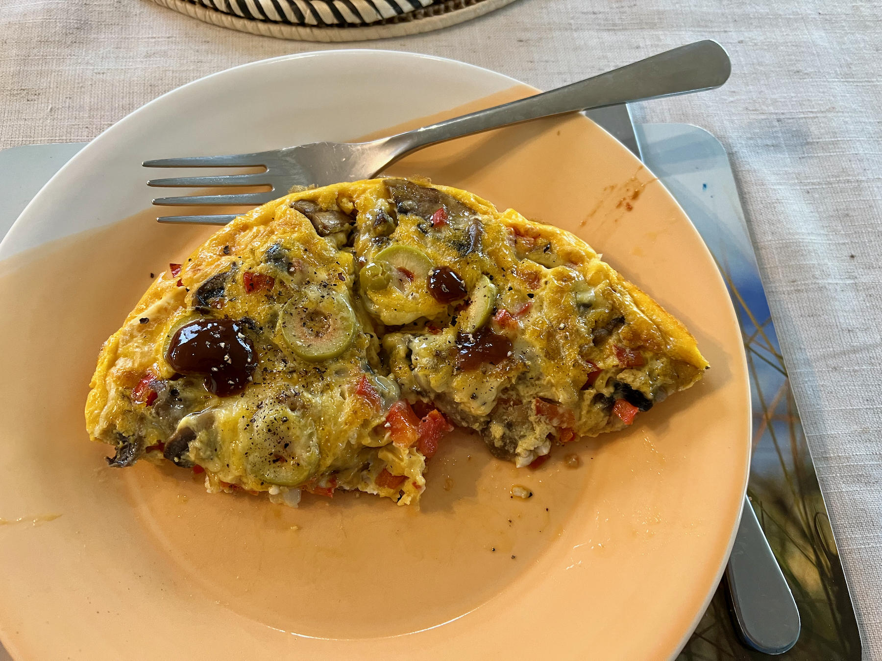 On a plate: half an omelette with cheese, olives, tomatoes and other ingredients. 