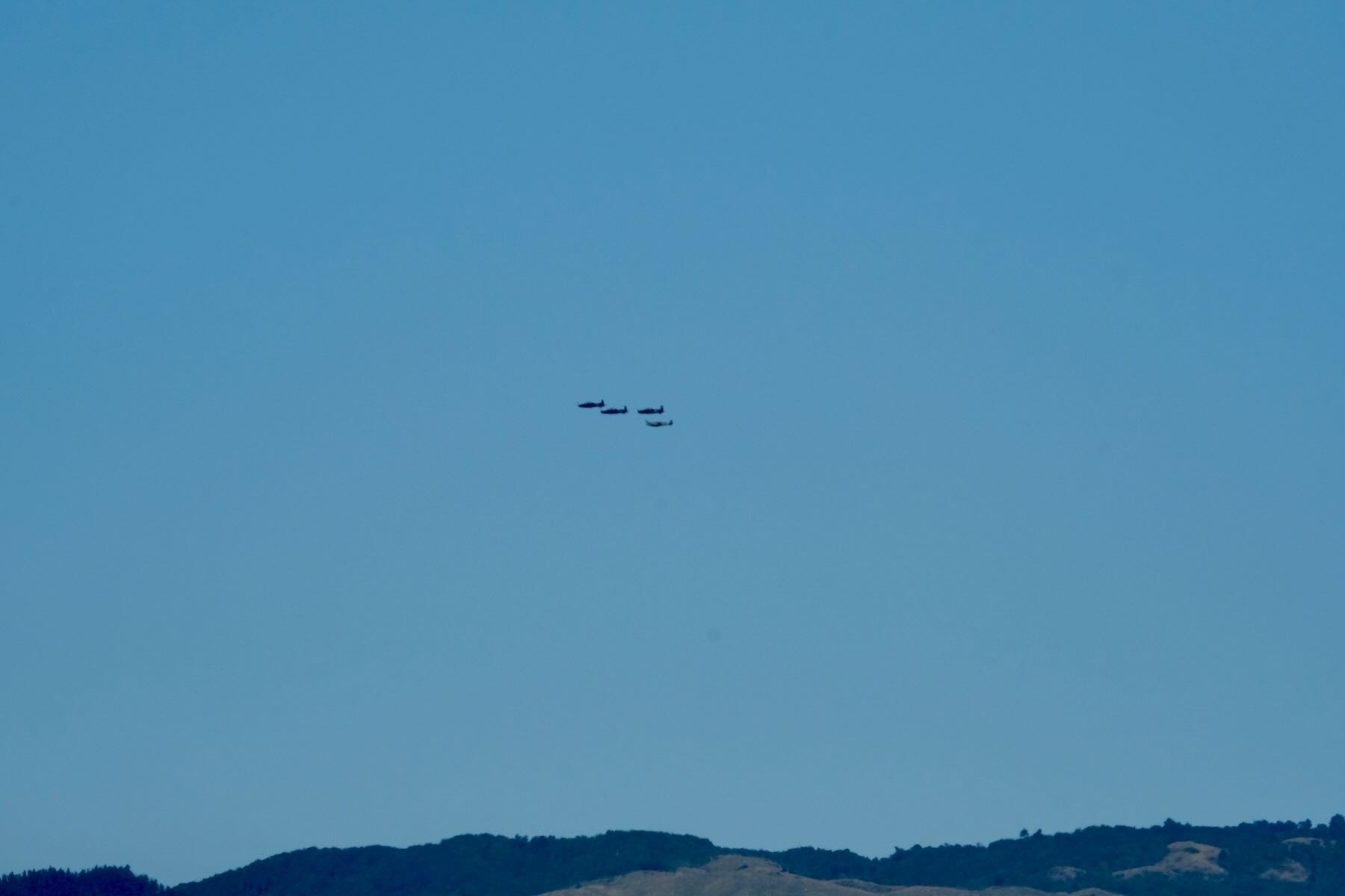 4 distant propeller planes in formation. 