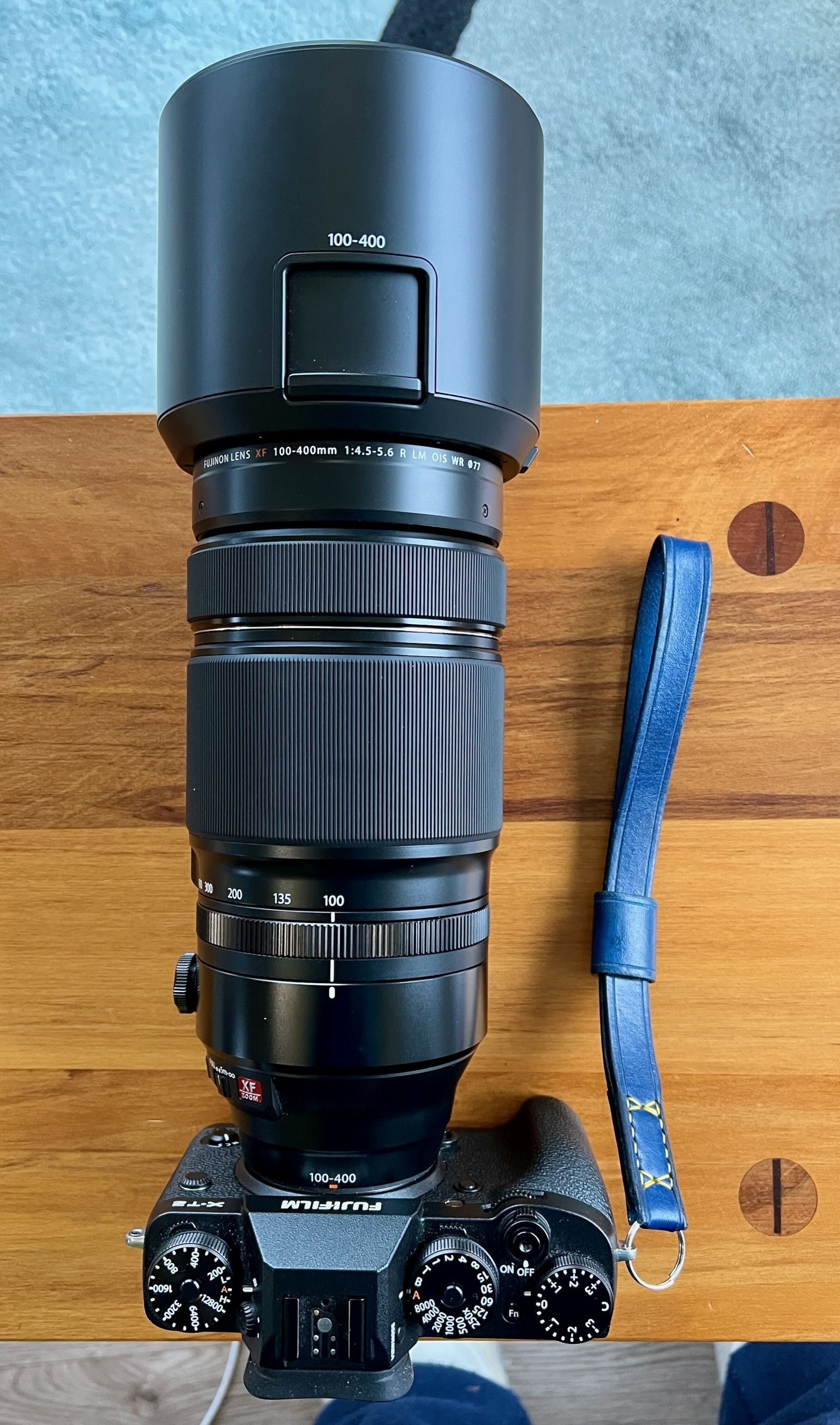 Camera with long lens and a blue leather wriststrap. 