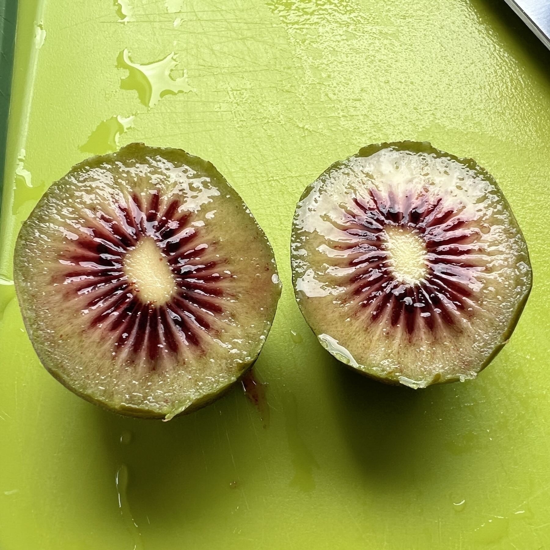 Small kiwifruit cut open, with red centre. 
