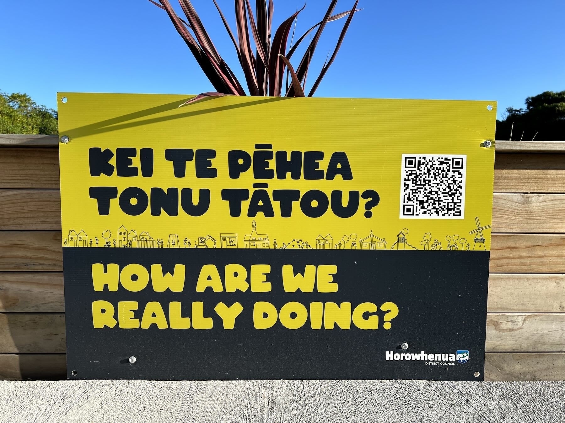 Yellow and black bilingual sign in an outdoor public setting. 