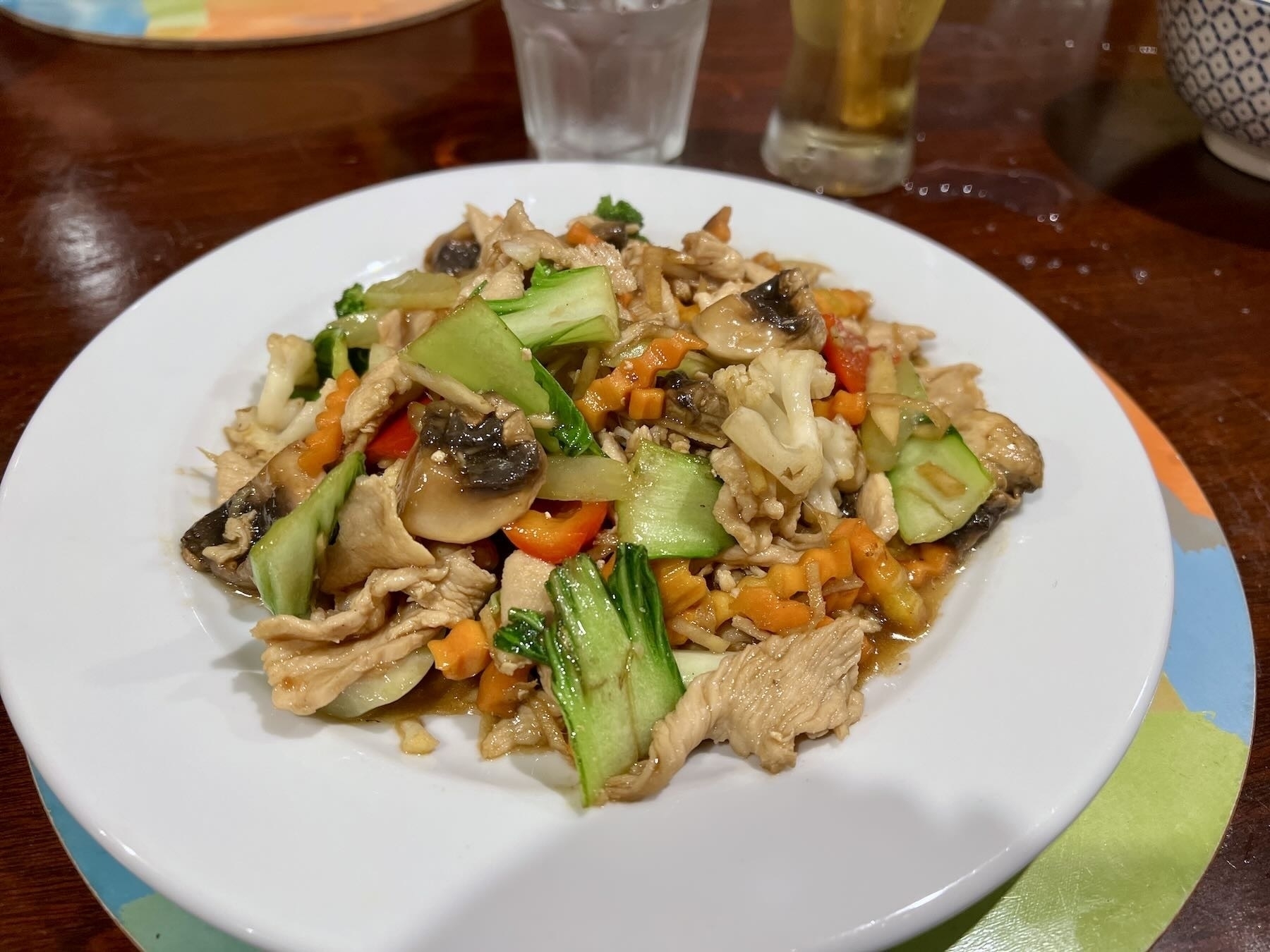 A plate of stir fry chicken with fresh vegetables and ginger. 