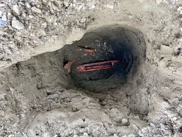 Orange conduit has been cut to reveal the cable inside. 