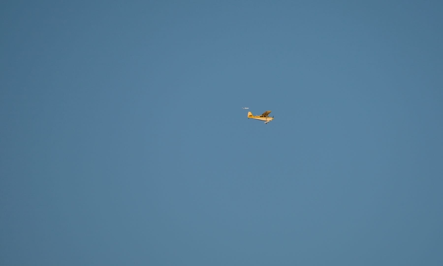 Small plane in late sunshine, with white dot nearby (behind). 