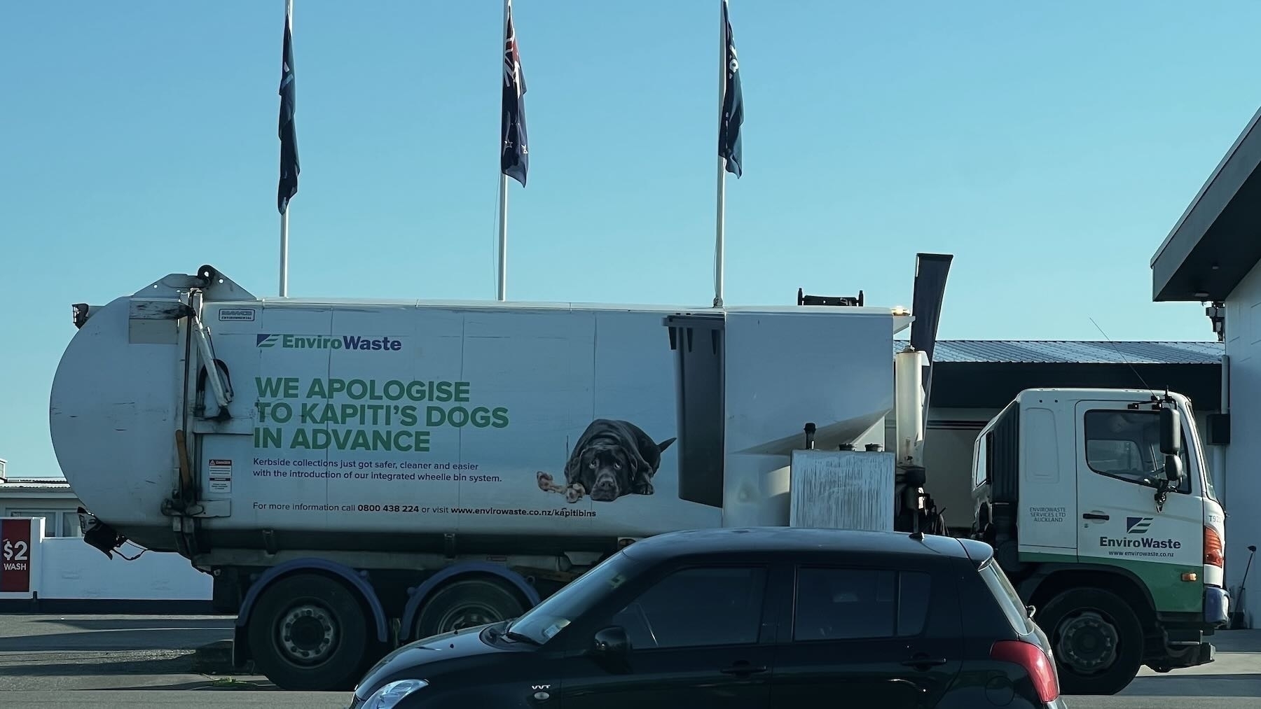 Rubbish truck has an apology to dogs on its side. Beside the words a picture shows a sad dog looking at a rubbish bin. 