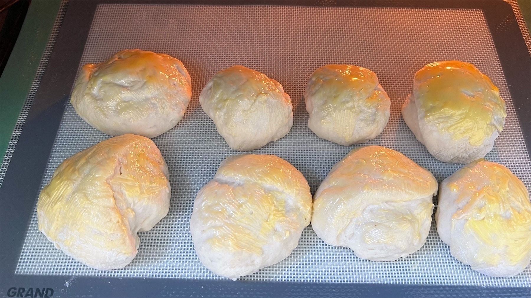 Rolls brushed with butter on their way into the oven. 