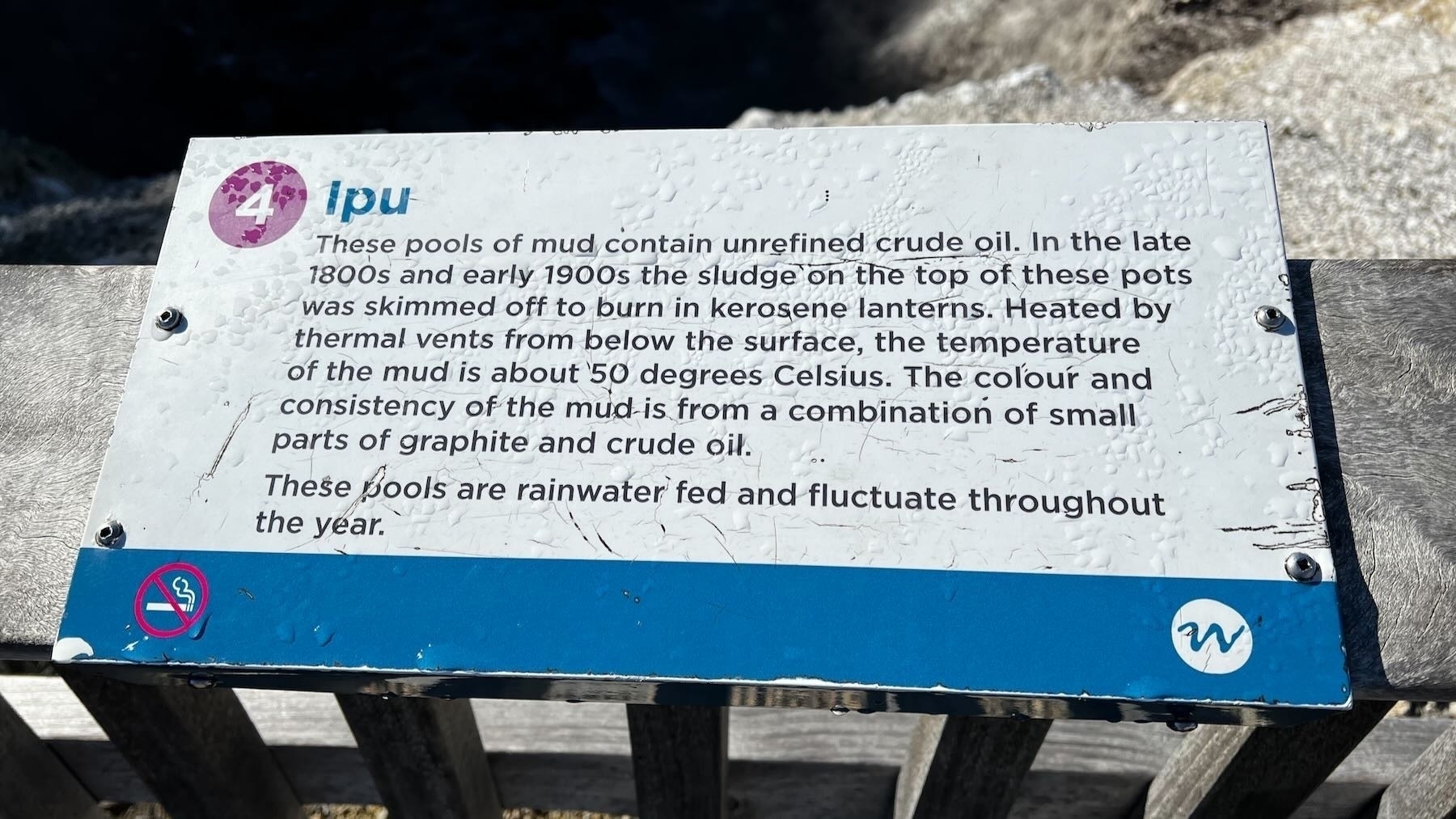 Sign saying some pools of mud contain unrefined crude oil. 