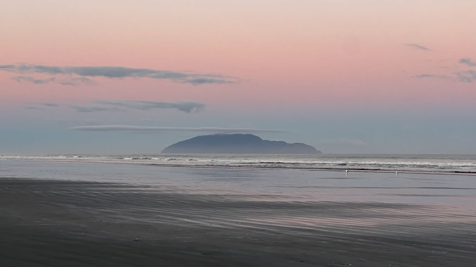 Kāpiti island cloud, a long and thin line seeming to balance on the peak. 