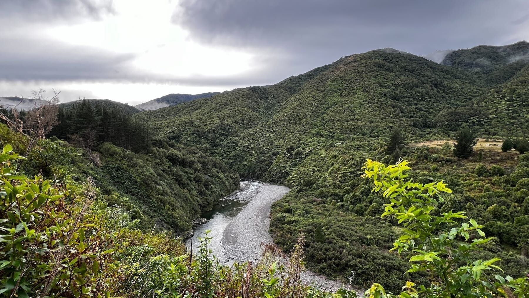 Lush green hills with a small river flowing through the valley below. 